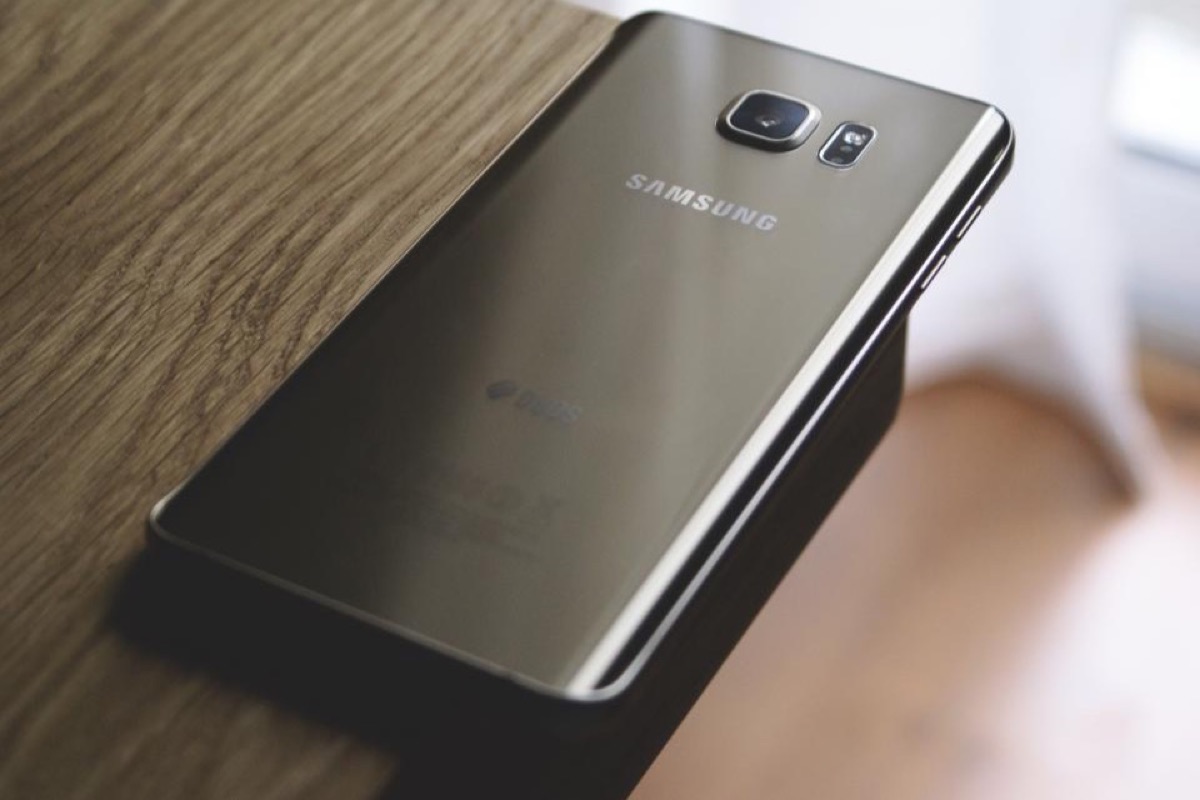 A smartphone lying face down on a wooden table.