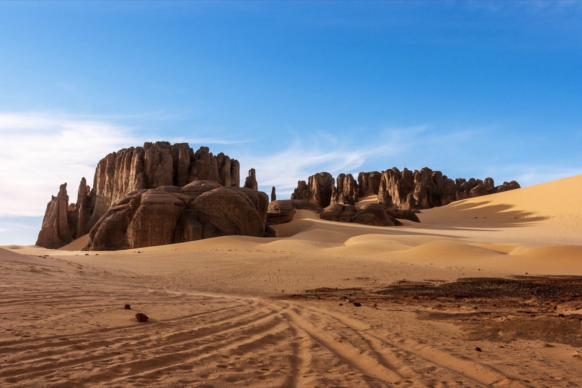 A rock formation rising out of the sand dunes of the Algerian Sahara.